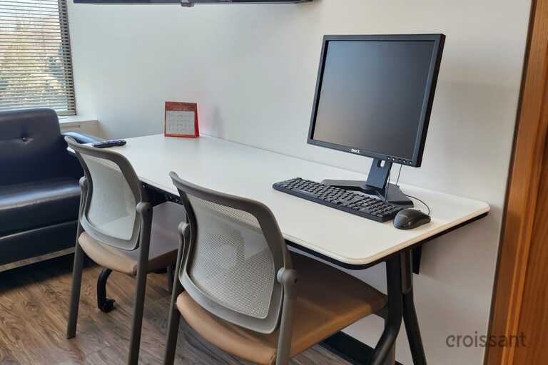 a desk with a computer and a chair in a room