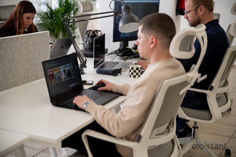 a group of people sitting at a table using a laptop