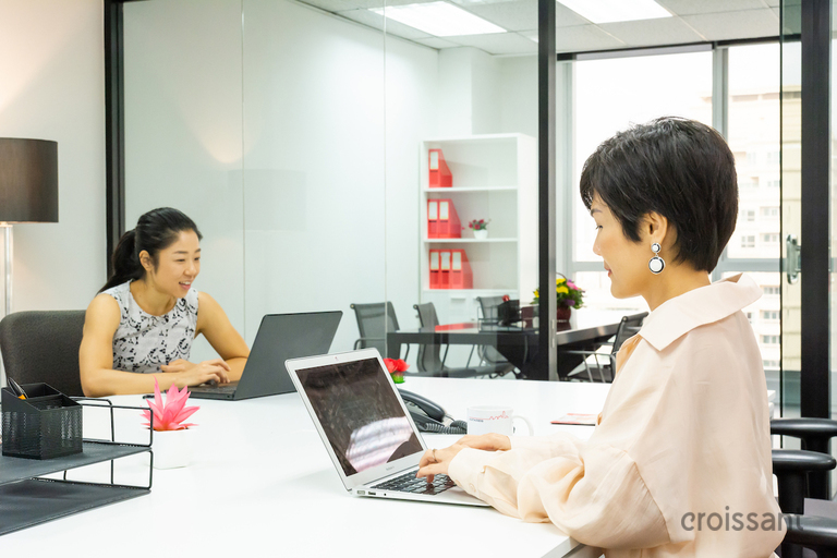 a man and a woman sitting at a table using a laptop