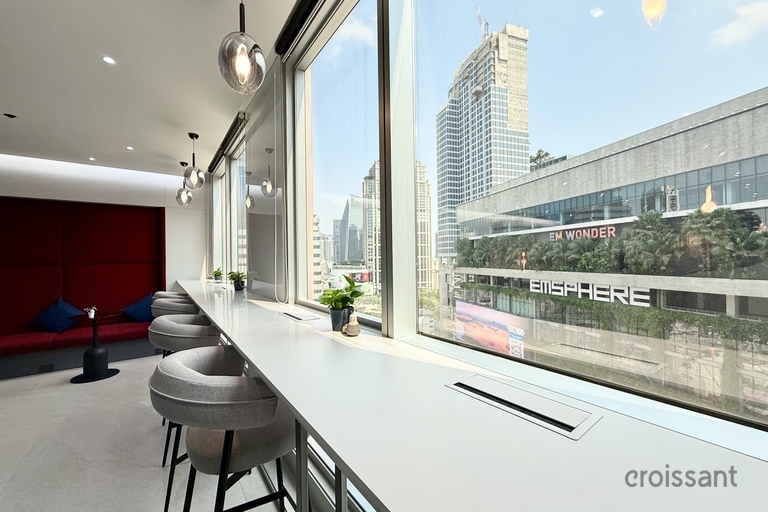 a long white countertop with stools and a window with a city view
