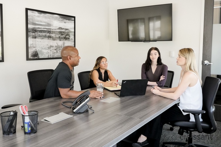 a group of people sitting at a table using a laptop