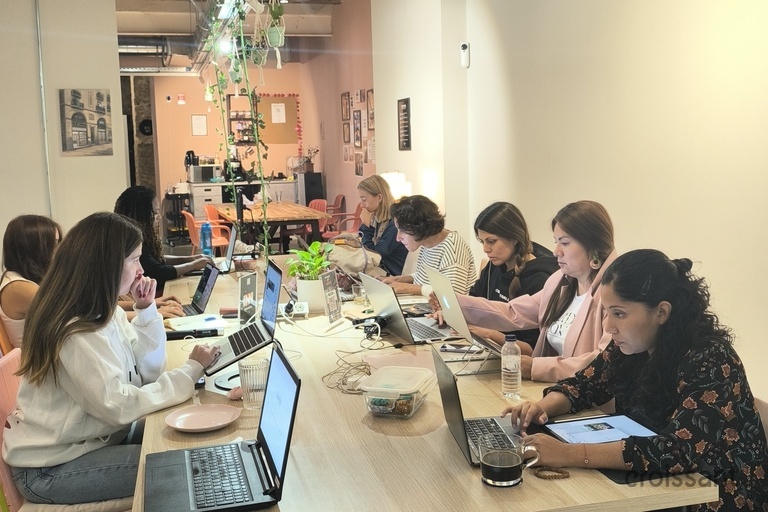 a group of people sitting at a table using a laptop computer
