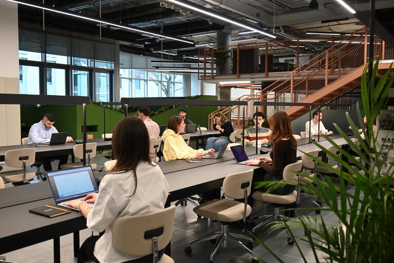 a group of people sitting at a table using a laptop computer