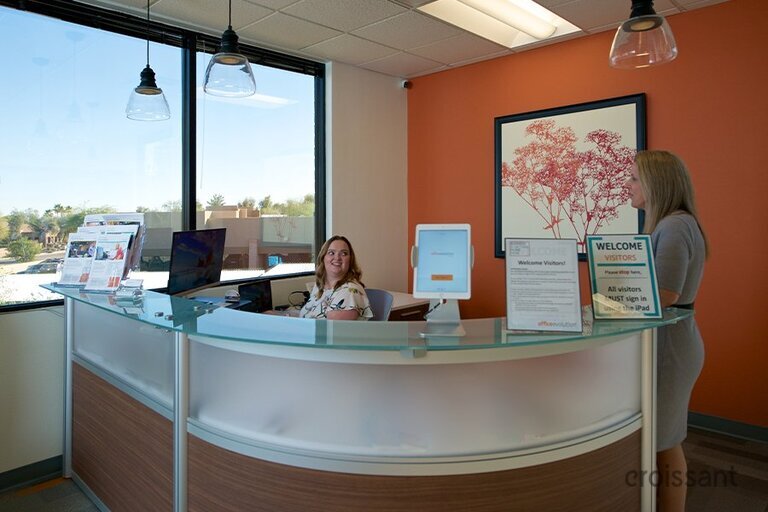 a group of people sitting at a desk in front of a window