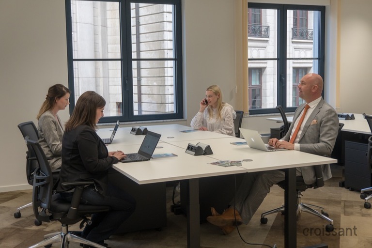 a group of people sitting at a desk in front of a laptop