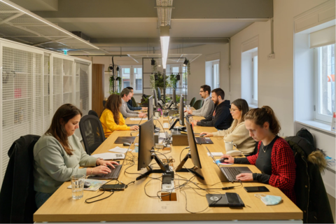 a group of people sitting at a table using a laptop computer