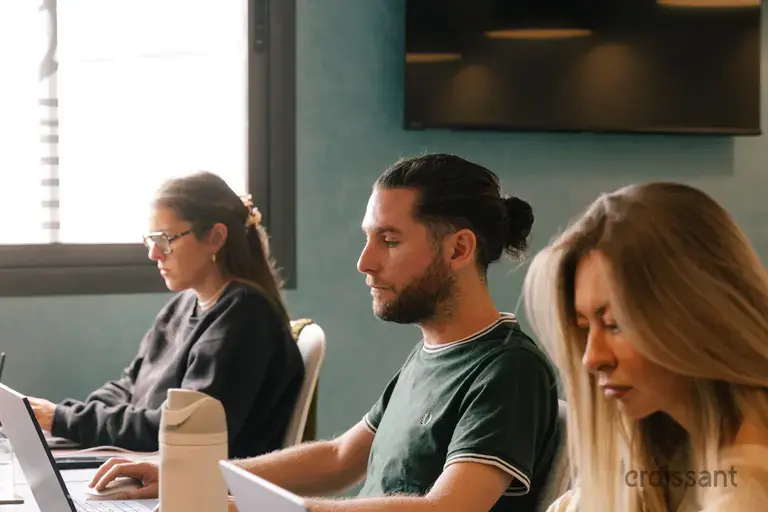 a group of people sitting at a table with laptops